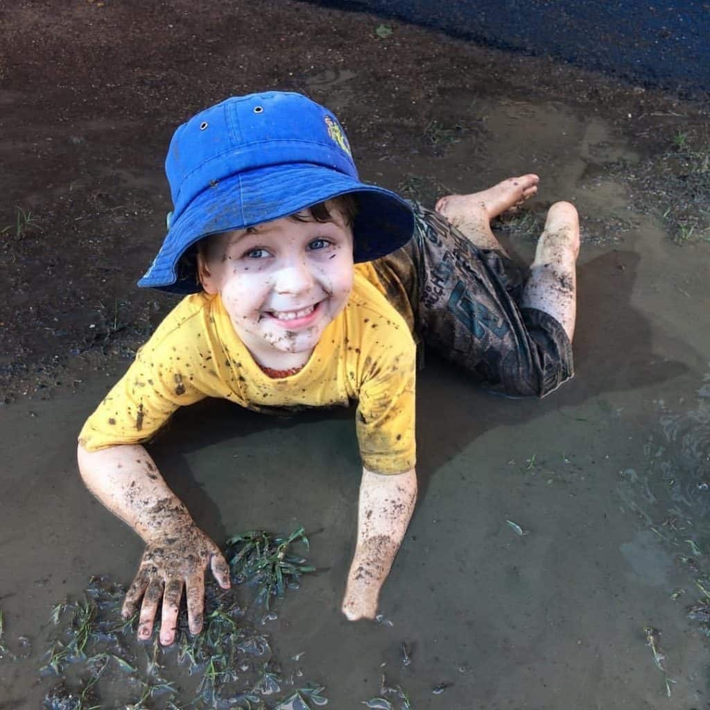 Child "born to be wild" plays outside with water and mud at childcare centre