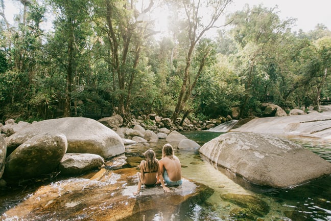 Couple sit on rock, partially in water at Josephine Falls 