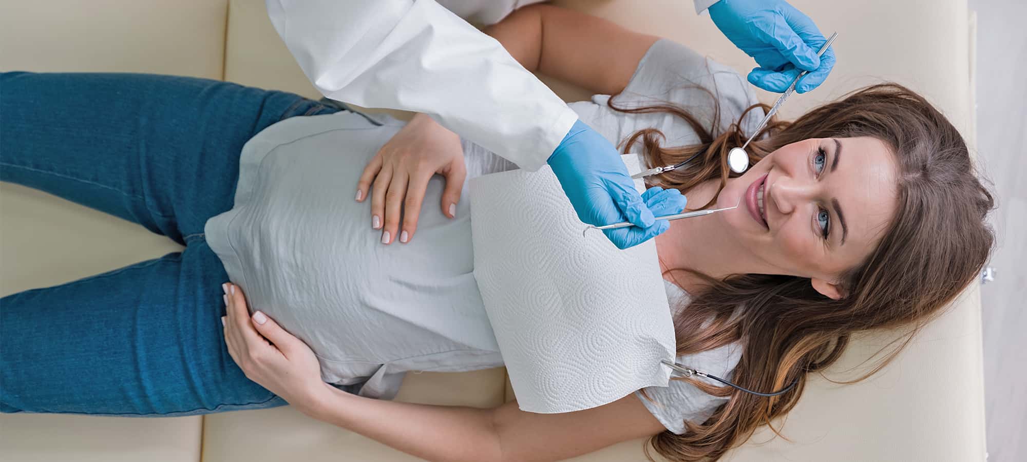 Pregnant woman lays on dental chair as dentist checks her teeth